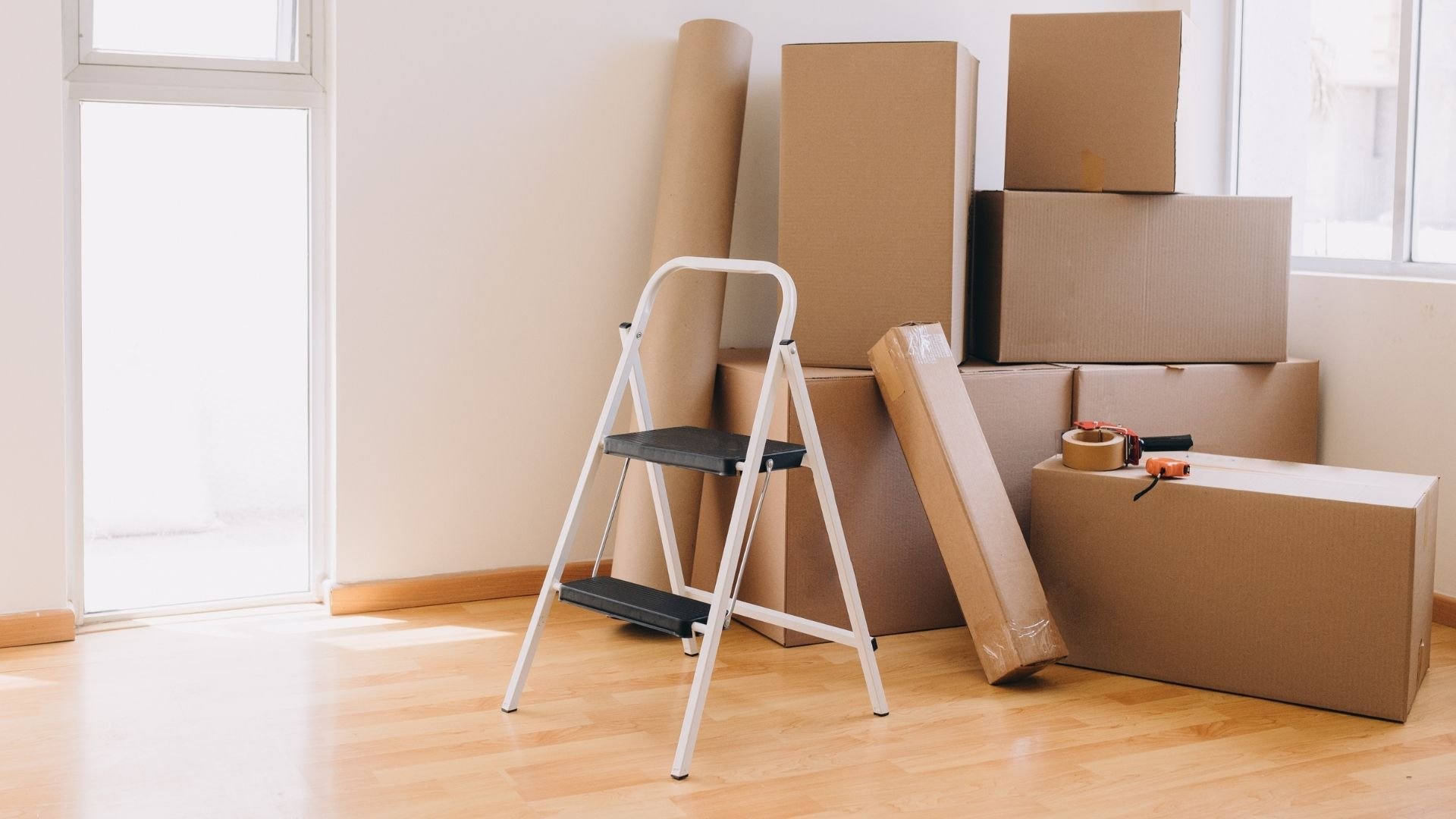 Moving boxes, ladder, and packing supplies in an empty room ready for relocation